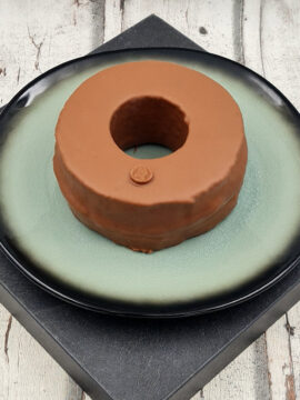 Baumkuchenring mit Vollmilchschokolade auf einem dekorativen Teller der Marke Goethe Chocolaterie