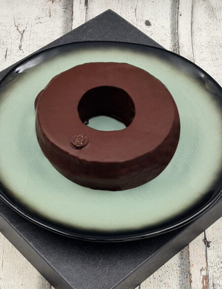 Baumkuchenring mit Zartbitterschokolade auf einem dekorativen Teller der Marke Goethe Chocolaterie